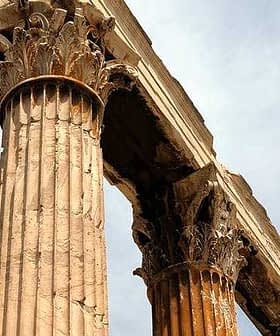 Close-up view of ancient Greek columns featuring Corinthian capitals and weathered stone. - Olive Oil Times