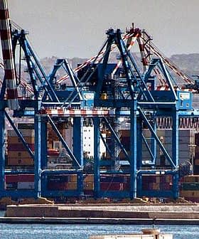 Loading cranes at a port with stacked shipping containers in the foreground. - Olive Oil Times
