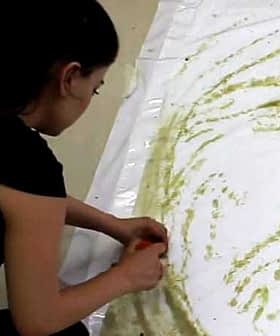 Individual applying olive oil to a large sheet of white paper to create artwork. - Olive Oil Times