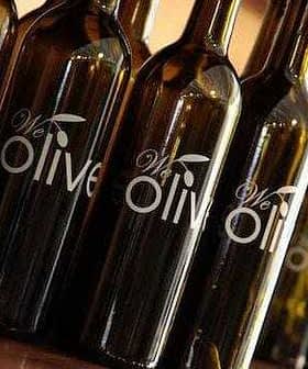 Several dark glass bottles with a label that reads 'We Olive' displayed in a row. - Olive Oil Times