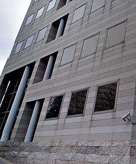 Exterior view of a modern office building with large windows and concrete pillars. - Olive Oil Times