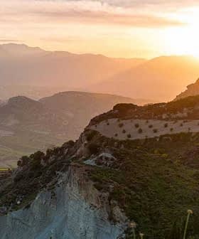 Sunset view over a mountainous landscape with rolling hills and olive trees. - Olive Oil Times