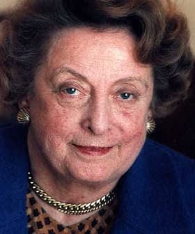 Close-up portrait of a woman with curly hair and blue eyes wearing a blue jacket. - Olive Oil Times