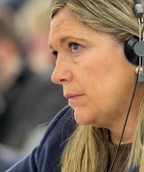 Woman wearing headphones, focused on a discussion during a conference or meeting. - Olive Oil Times