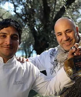 Two chefs posing together, one holding a bottle of yuzu olive oil in an outdoor setting. - Olive Oil Times