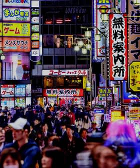 Busy street in Tokyo filled with people and illuminated neon signs in various colors and languages. - Olive Oil Times