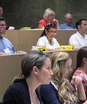 Group of individuals seated in a classroom, attentively listening during a presentation. - Olive Oil Times
