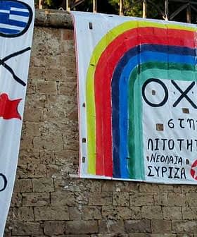 Two large banners with political messages and colorful designs displayed on a stone wall. - Olive Oil Times