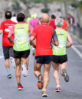Three runners wearing colorful athletic clothing jogging on a road during a running event. - Olive Oil Times