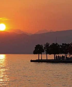 Sunset view over Lake Garda with silhouettes of trees and mountains in the background. - Olive Oil Times