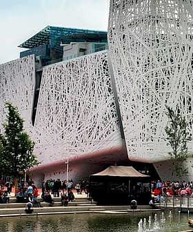 Contemporary building featuring a unique, intricate exterior design with people gathered around a water feature. - Olive Oil Times