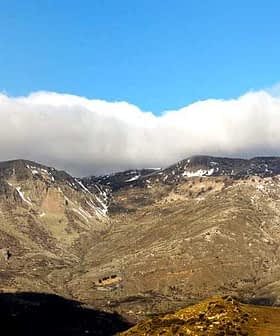 Mountain landscape featuring rugged terrain and clouds in the sky above. - Olive Oil Times