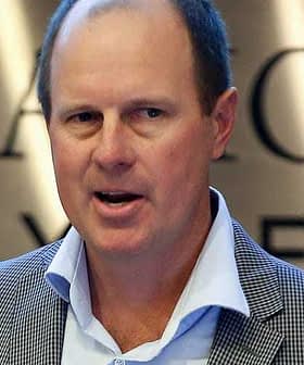 Man in a checkered blazer speaking at a podium during an event. - Olive Oil Times