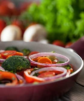 A pan filled with a colorful mix of sliced vegetables including broccoli, carrots, and red onions. - Olive Oil Times
