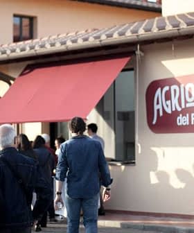 People walking towards the entrance of Agrilosteria del Frantoio with a red awning. - Olive Oil Times