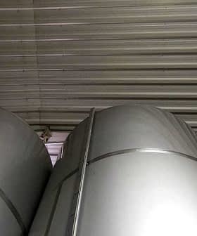 Stacked metal storage tanks in a warehouse with a metallic finish and cylindrical shape. - Olive Oil Times