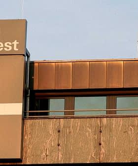 Signage of Stiftung Warentest displayed on a building exterior with a large plus symbol. - Olive Oil Times