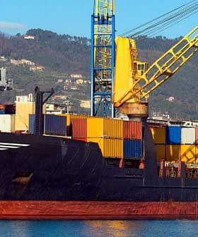 Cargo ship docked at a port with various colorful shipping containers stacked on board. - Olive Oil Times