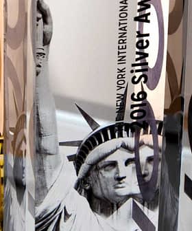 Three awards featuring the Statue of Liberty design with gold and silver text indicating the year and award type. - Olive Oil Times