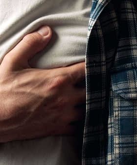 Individual in a plaid shirt holding their chest with a pained expression. - Olive Oil Times