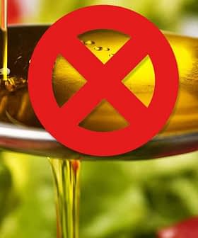 Spoon pouring olive oil with a red prohibition symbol overlaying the image. - Olive Oil Times