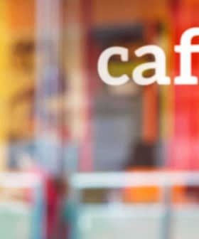 The word 'café' displayed on a glass window with a blurred background. - Olive Oil Times