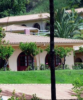 A residential complex featuring buildings with red doors and landscaped greenery. - Olive Oil Times