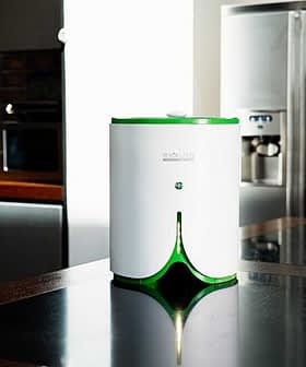 Compact white and green kitchen appliance with a button on top, placed on a dark countertop. - Olive Oil Times