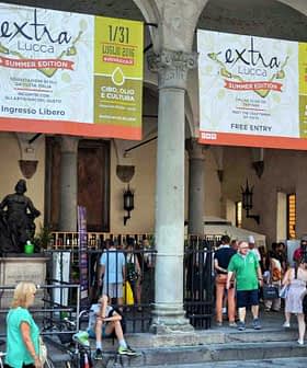 Entrance to an event in Lucca featuring large banners and people walking by. - Olive Oil Times