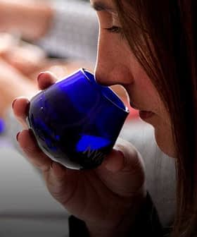 Individual smelling olive oil from a blue tasting cup during a tasting session. - Olive Oil Times