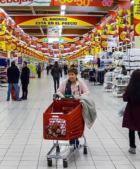 View of a supermarket aisle with shoppers and various products displayed on shelves. - Olive Oil Times