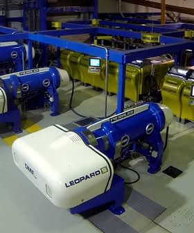 Industrial olive oil production equipment with blue and yellow machines in a processing facility. - Olive Oil Times