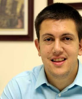 Young man with short dark hair wearing a light blue shirt, smiling at the camera. - Olive Oil Times