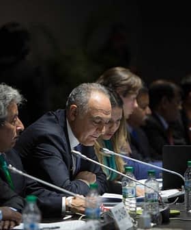 Group of officials seated at a conference table during a meeting, with a speaker addressing the group. - Olive Oil Times