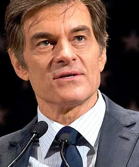 Man in a suit speaking at a podium with a microphone against a backdrop of stars. - Olive Oil Times