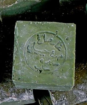 A close-up of a traditional Aleppo soap bar with an embossed design on its surface. - Olive Oil Times