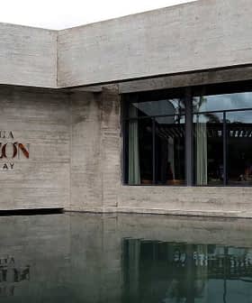 Modern architectural structure of Bodega Garzon with water reflection in front. - Olive Oil Times