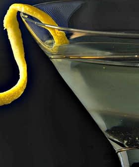 A martini glass filled with a clear liquid and a lemon twist garnish on the rim. - Olive Oil Times