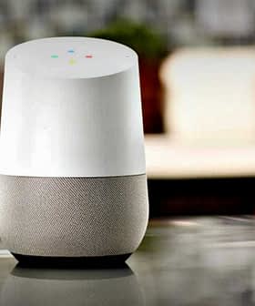 Google Home smart speaker with a white top and gray fabric base on a kitchen countertop. - Olive Oil Times