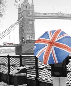 Individual holding a Union Jack umbrella while standing near Tower Bridge in winter. - Olive Oil Times