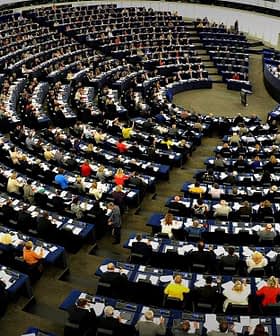Interior view of the European Parliament with numerous members seated in a circular arrangement. - Olive Oil Times