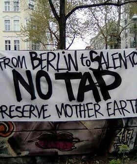 A protest banner reading 'From Berlin to Salento No Tap Preserve Mother Earth' displayed in an urban setting. - Olive Oil Times