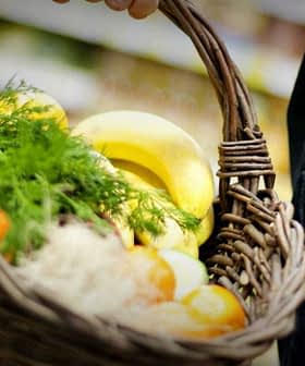 A person holding a woven basket filled with various fresh fruits and vegetables. - Olive Oil Times
