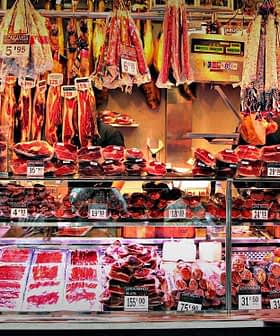 A variety of meats displayed in a market stall with price tags visible. - Olive Oil Times