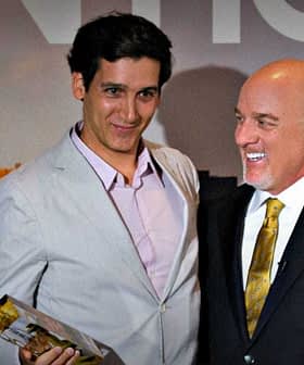 Two men standing together at an award ceremony, one holding a trophy and the other smiling. - Olive Oil Times