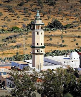 A minaret located in a rural area, surrounded by olive trees and agricultural land. - Olive Oil Times
