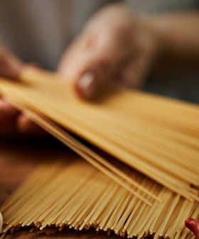 Raw spaghetti, tomatoes, garlic, mushrooms, yellow bell pepper, and eggs arranged on a wooden surface. - Olive Oil Times