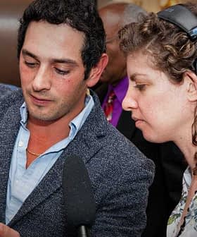 A man pouring olive oil into a glass while a woman observes at an event. - Olive Oil Times
