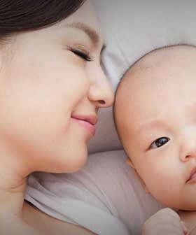 A mother and her baby lying close together, both looking at the camera with soft expressions. - Olive Oil Times