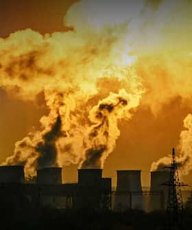 Smoke billowing from multiple smokestacks of an industrial power plant against a sunset backdrop. - Olive Oil Times